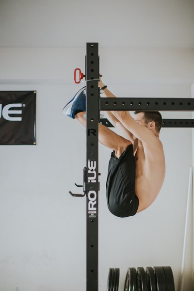 Atleta de lado haciendo toes to bar en un rack de crosstraining